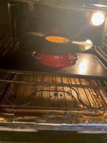 Thrifted vinyl record on top of strainer inside oven