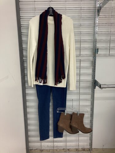 Women's outfit with cream coloured sweater, scarf, and blue jeans.