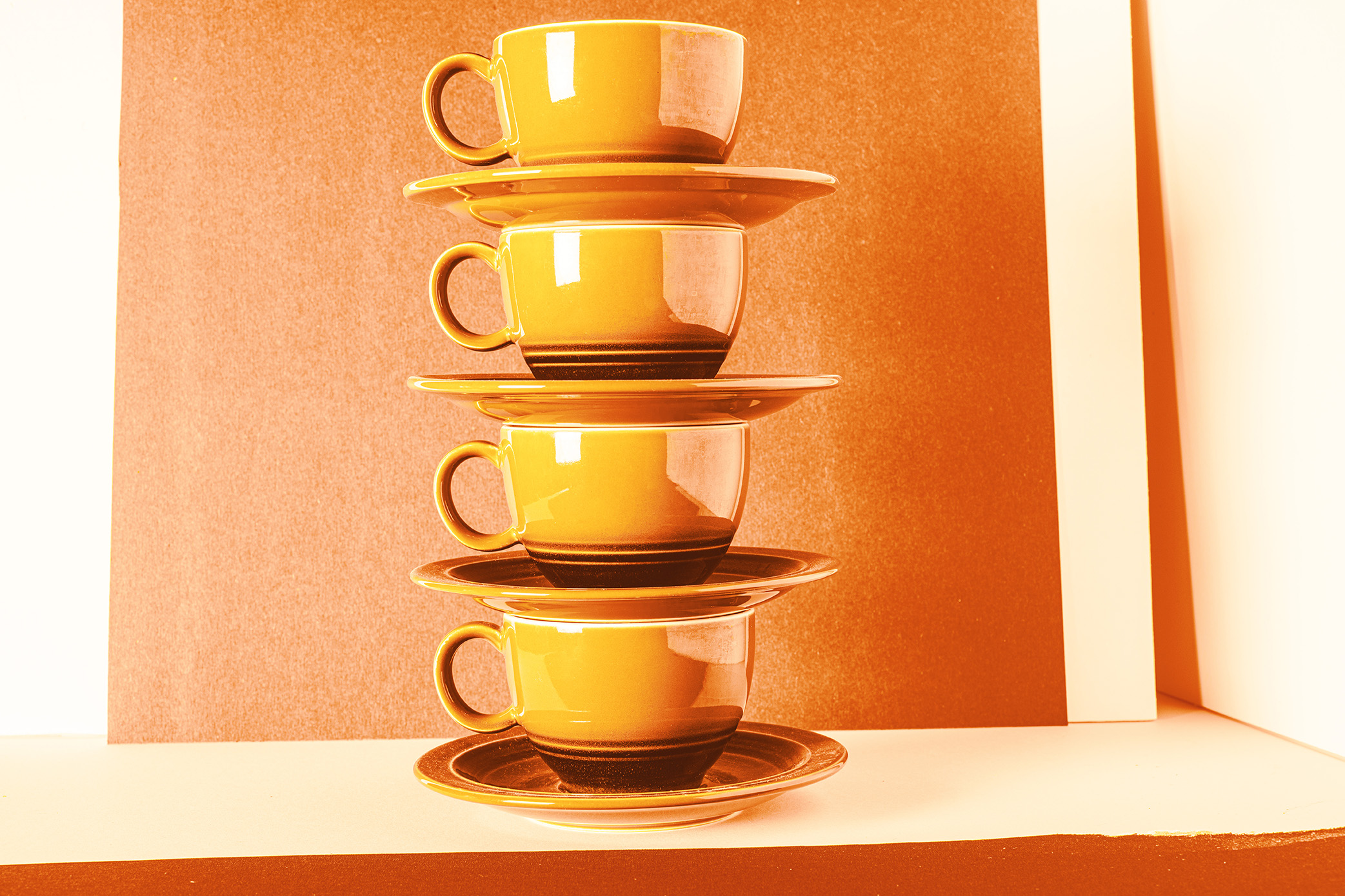 Impact report close-up photo of yellow orange teacups and saucers stacked on top of each other