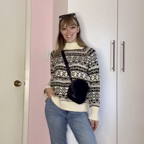 Young woman wearing a white thrifted knit sweater with denim and crossbody purse from local thrift shop