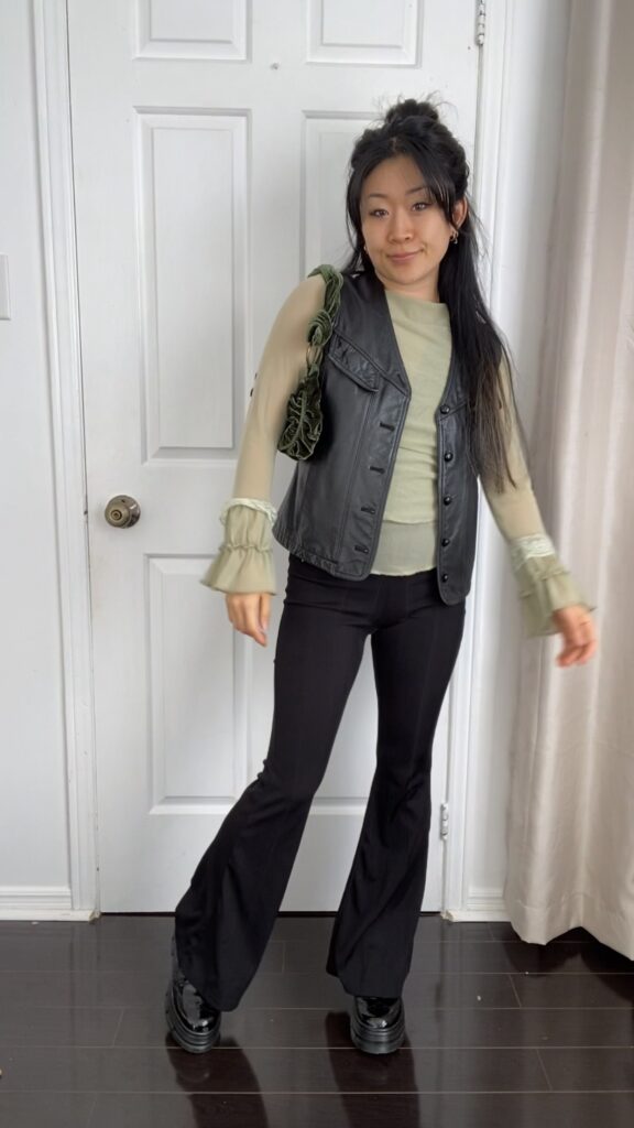 Anna wearing green top and black yoga pants with black vest, boots and purse - styled look #1