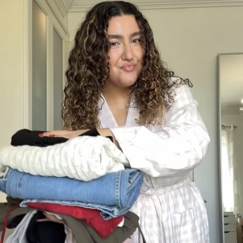 Vanessa holding clothes pile from thrift haul