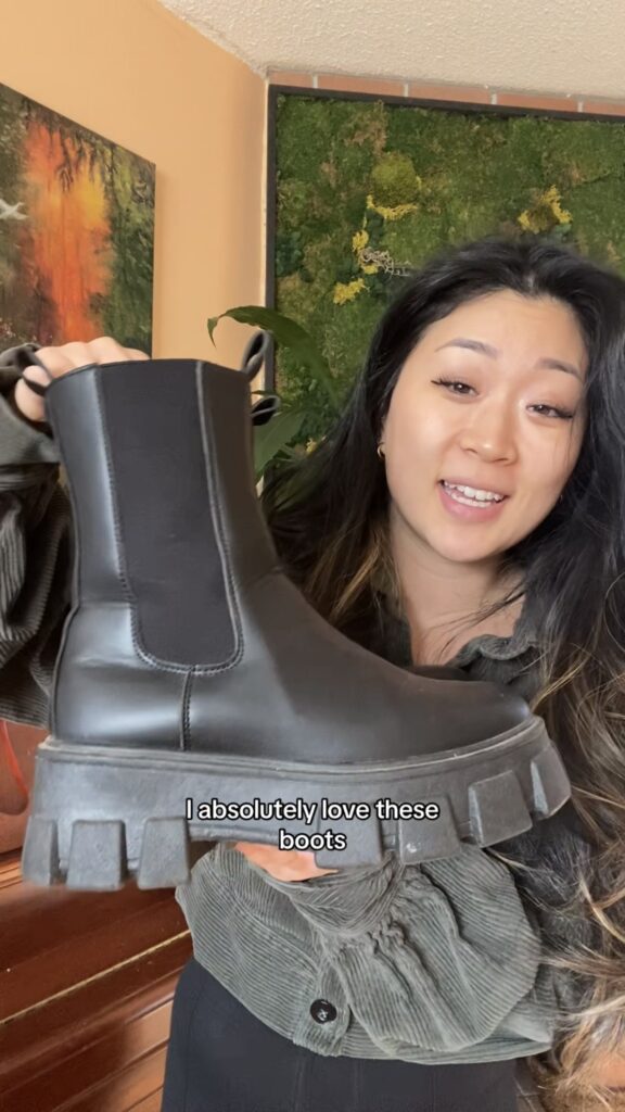 Anna holding thrifted black boots