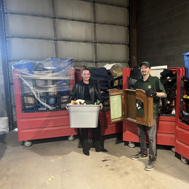 Just Junk Calgary employee standingwith Thrift Store attendant in front of bins of corporate partnership donations